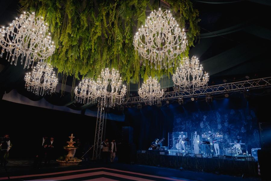 Crystal chandeliers hanging from a ceiling of greenery