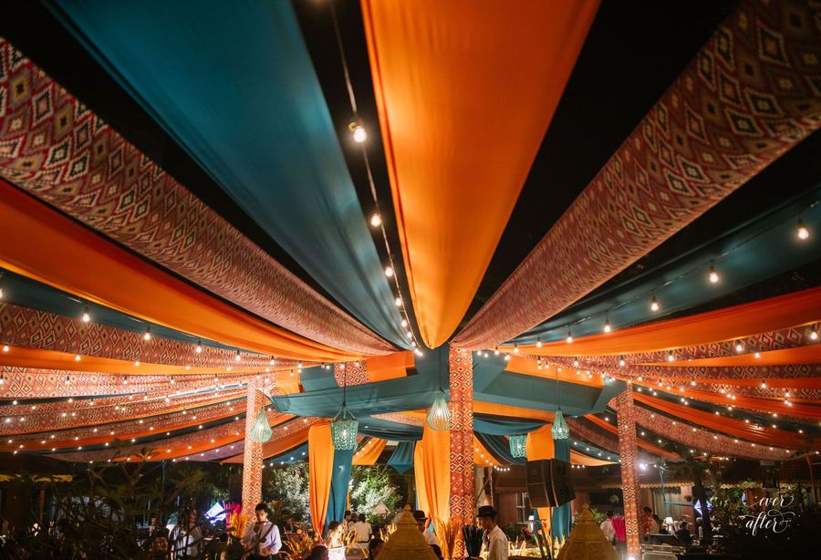 Canopy of teal and orange drapes strung with lights