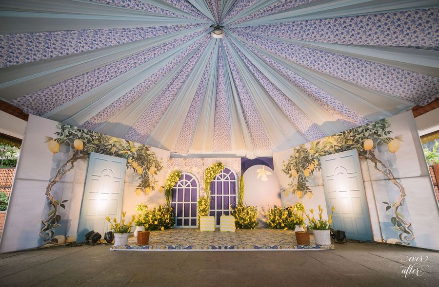 Pastel pleated tent over a garden-arched ceremony stage
