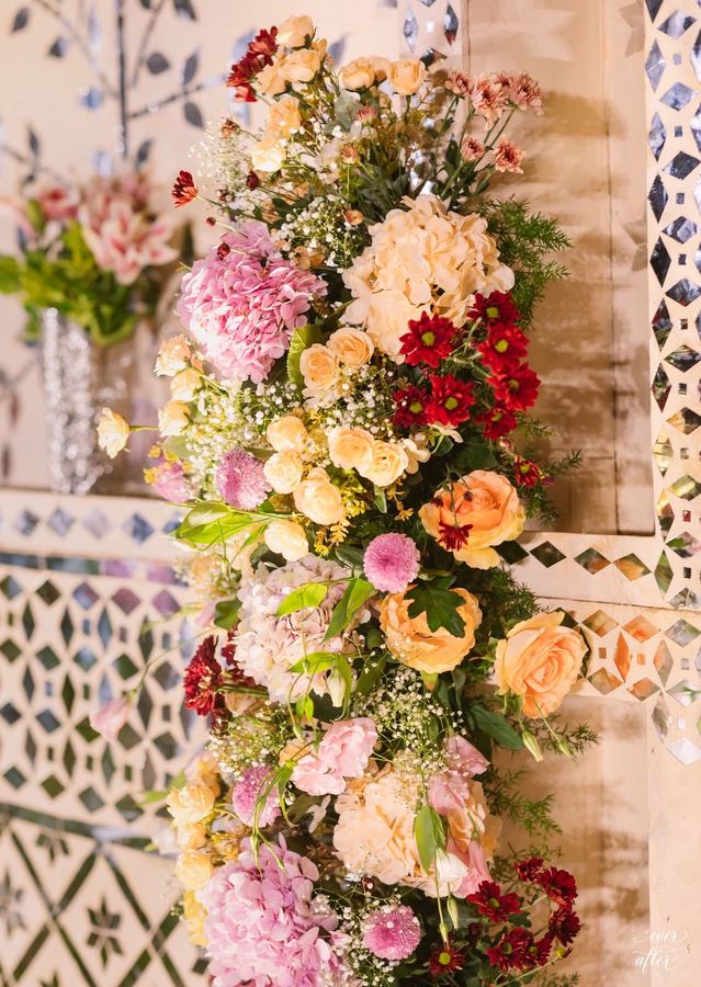 Cascade of peach, pink and red roses against mirror work