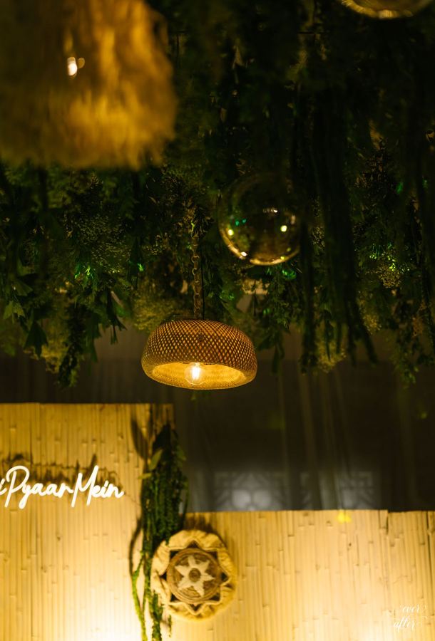 Rattan lanterns and glass orbs over a neon-signed bamboo wall