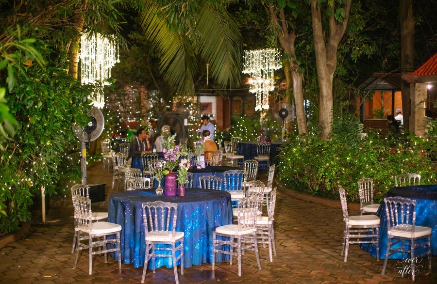 Garden dinner tables in blue with crystal chandeliers in the trees