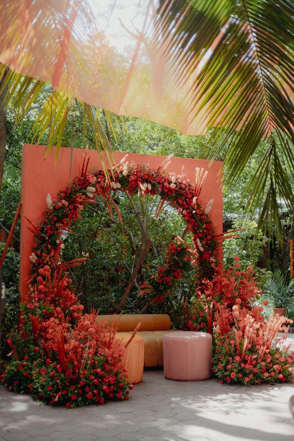 Circular arch of red roses before a coral backdrop