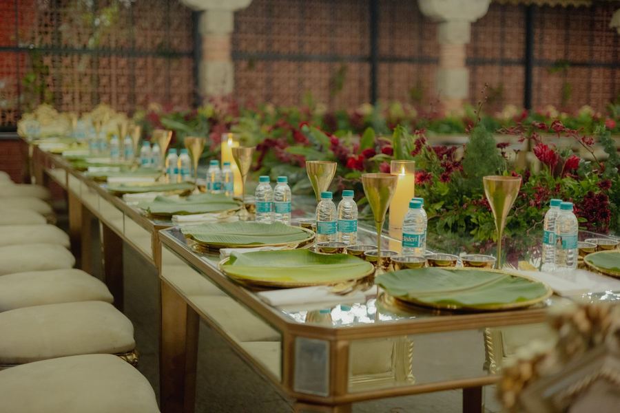 Long table set with gold chargers and banana leaves