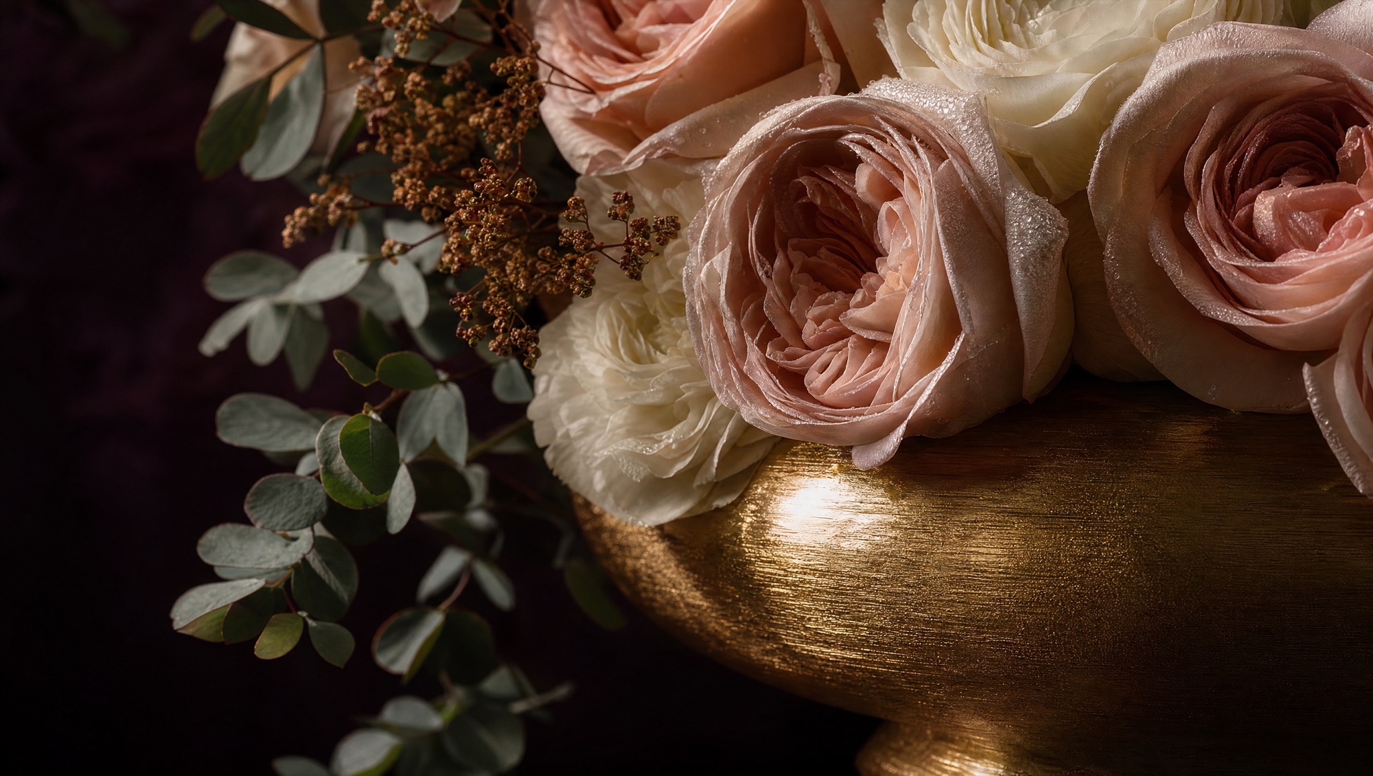 Close detail of a floral arrangement in a brushed gold vessel