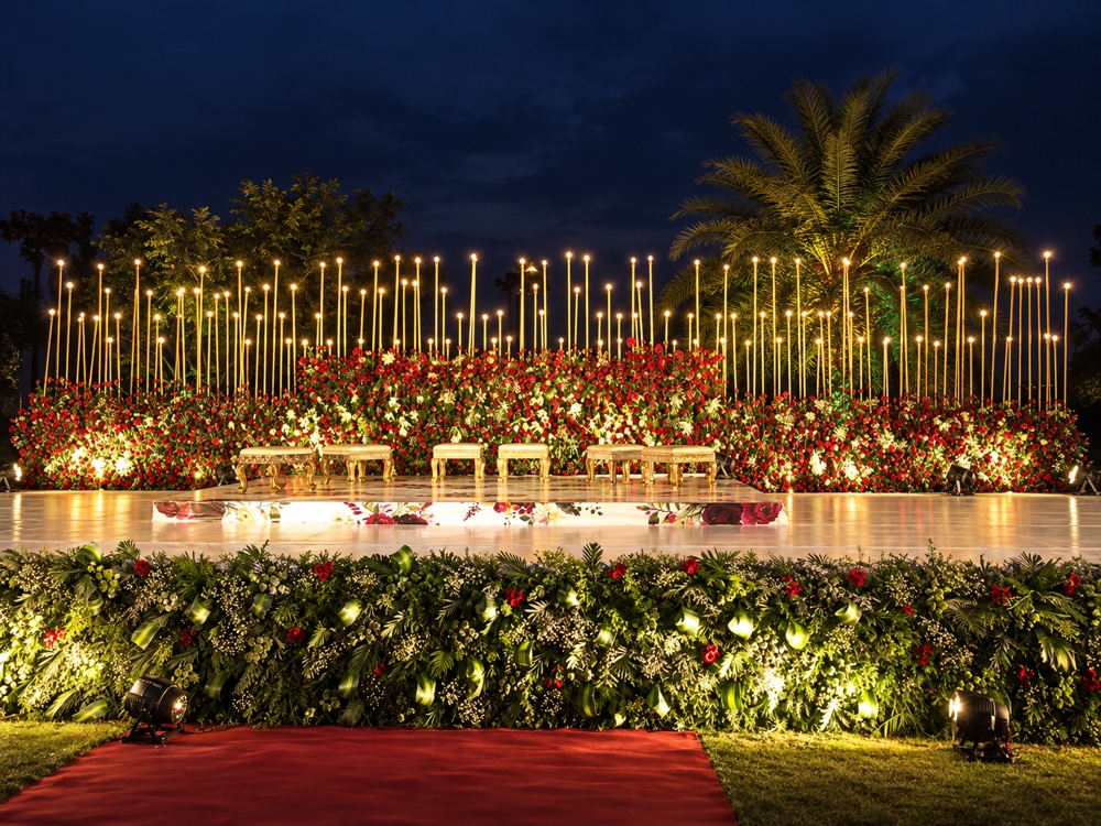 Torch-lit garden stage with red and white floral backdrop